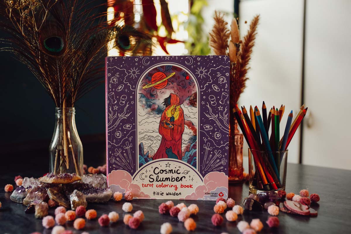Cosmic Slumber Tarot Coloring Book auf dekoriertem Tisch mit Buntstiften